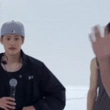 a man in a baseball cap is holding a microphone while another man waves .