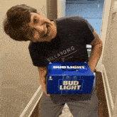 a man wearing a billabong shirt is holding a bud light box