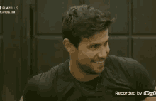 a man in a black shirt is laughing in front of a door .