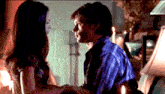 a man and woman are looking at each other in a dark room
