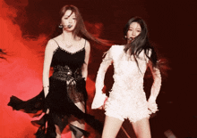 a woman in a black dress and a woman in a white dress are dancing on a stage
