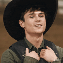a man wearing a cowboy hat and a vest with a netflix logo on it