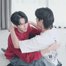 a man in a white shirt with the letter h on the back is hugging another man