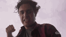 a man in a red shirt is making a funny face while holding his fist in the air .