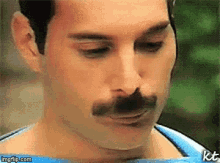 a close up of a man 's face with a mustache and the letters kt on the bottom