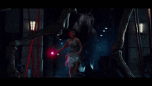 a woman in a white tank top is holding a pink light in front of a large skeleton