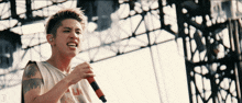 a man with a tattoo on his arm singing into a microphone with the letter d below him