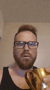 a man with glasses and a beard holds a trophy
