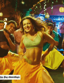 a woman in a green top and yellow skirt is dancing in a crowd