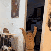 a little boy is standing in a room with his arms outstretched .