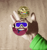 a hand is holding a smiley face and a purple ball with a face on it