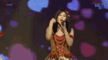 a woman is singing into a microphone on a stage .
