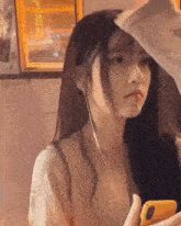 a girl with long hair is wearing headphones and holding a cell phone in her hand .