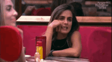 a woman sits at a table in front of a mirror with the words apowerrec big brother brasil on the bottom right