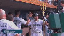 a baseball player wearing a mariners jersey high fives his teammates