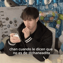 a man sitting at a table looking at his phone with the caption chan cuando le dicen que no es de