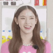 a woman wearing a pink sweater and a white headband is sticking out her tongue .