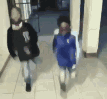 a blurry picture of two people walking down a hallway with one wearing a blue jacket