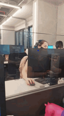 a woman wearing a mask sits at a dell computer