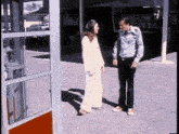 a man and woman are standing in front of a phone booth