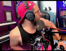 a man wearing headphones and a red hat sitting in front of a microphone