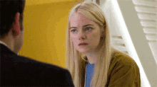 a woman with blonde hair and blue eyes looks at a man in a suit