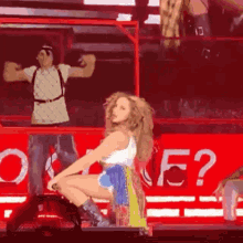 a woman is kneeling down on a stage in front of a red sign that says one e?