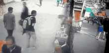 a group of people are walking down a street and a man is carrying a backpack .