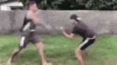two men are boxing in the grass in a yard .