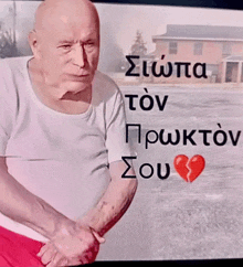 a man with a broken heart is standing in front of a screen with greek writing