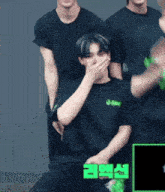 a man in a black shirt is covering his mouth with his hands