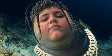 a man with dreadlocks and a chain around his neck looks like an eel