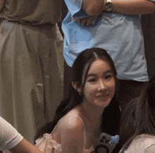 a woman in a pink dress is smiling while holding a phone