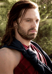 a man with long hair and a beard is wearing a red shirt and tie