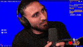 a man wearing headphones looks at the camera with a blue screen behind him