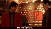 two men standing in front of a sign that says the same people