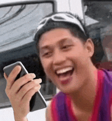 a man is laughing and holding a cell phone in his hand