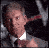 a man in a suit and tie is pointing at the camera .