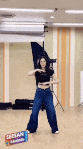 a woman is dancing in a room with a sign that says seesan on it .