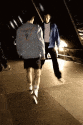 a man wearing a guess jacket is jumping in the air with another man