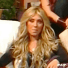 a woman with long blonde hair is sitting on a couch in a blurry photo that says rbd.gif