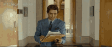a man in a suit and tie is holding a clipboard and looking at it