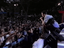 a man is standing on a stage in front of a crowd of people .