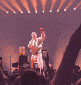 a man is singing into a microphone while a crowd holds up their phones