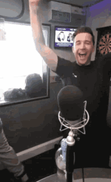 a man is standing in front of a microphone with his arm in the air