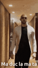 a man in a white jacket is walking down a hallway with the words ma duc la mata written on the bottom