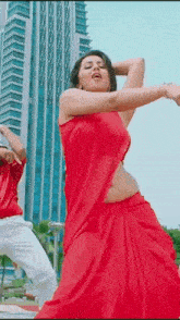 a woman in a red dress is dancing with a man in a red shirt .