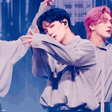 a man in a gray shirt is dancing with another man in a pink haired group