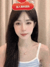 a woman wearing a white tank top and a necklace has a red heart on her head with chinese writing