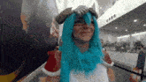 a woman in a blue wig stands in front of a sign that says ashley